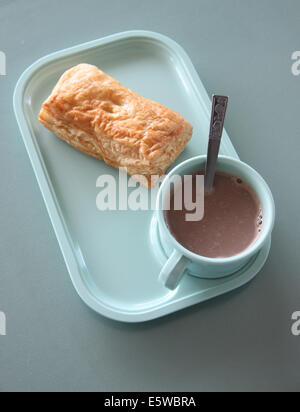 Patty e cioccolata calda in un piatto blu sul tavolo da pranzo. Foto Stock