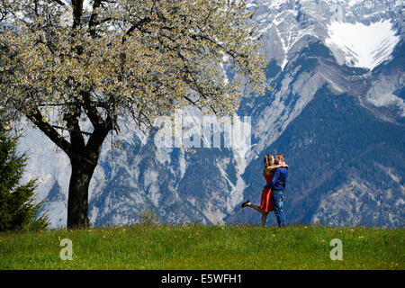 Gli amanti abbracciando accanto a un albero di fioritura in primavera, montagne sul retro, Tirolo, Austria Foto Stock