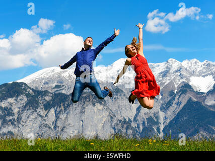 L uomo e la donna salta su un prato a primavera in montagna in retro, Tirolo, Austria Foto Stock