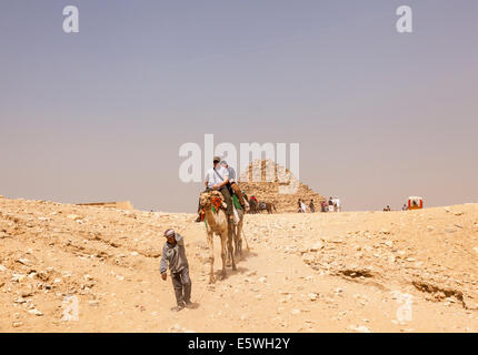 Piramidi, Egitto - turistico a dorso di un cammello dalla Grande Piramide di Giza in Egitto Foto Stock