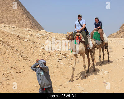 I turisti a cavallo di cammelli da la Grande Piramide di Giza in Egitto Foto Stock