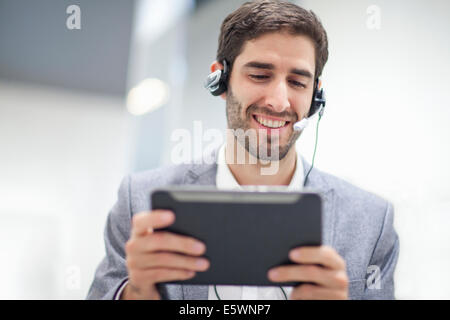 Giovane uomo che indossa la cuffia utilizzando tavoletta digitale Foto Stock