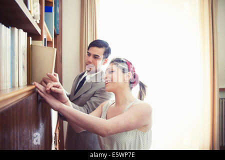 Giovane coppia vintage browsing libri sullo scaffale Foto Stock