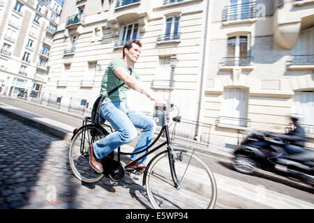 Metà maschio adulto ciclista di accelerare via acciottolata, Parigi, Francia Foto Stock