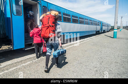 Vista posteriore di giovani escursionisti con zaini di salire a bordo di un treno Foto Stock