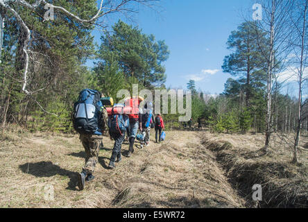 Vista posteriore di giovani escursionisti con zaini su pista forestale Foto Stock