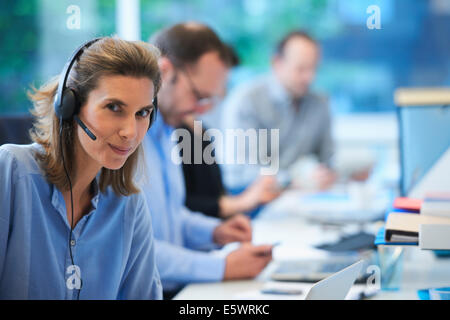 Donna che indossa cuffia telefonica in ufficio Foto Stock