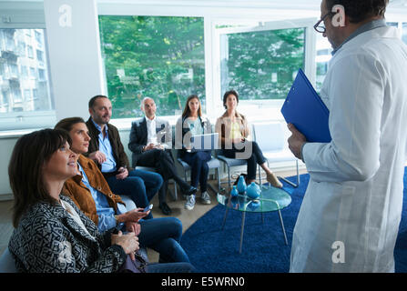 Gruppo di persone sedute, guardando l'uomo in labcoat Foto Stock