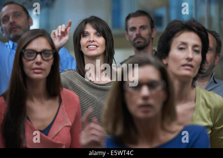 Gruppo guarda la presentazione, donna alzando la mano Foto Stock