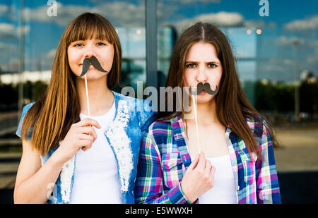 Ritratto di due giovani donne tenendo premuto fino baffi maschere in costume Foto Stock