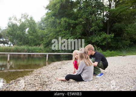 Fratelli e due sorelle seduta in chat sul lago Foto Stock