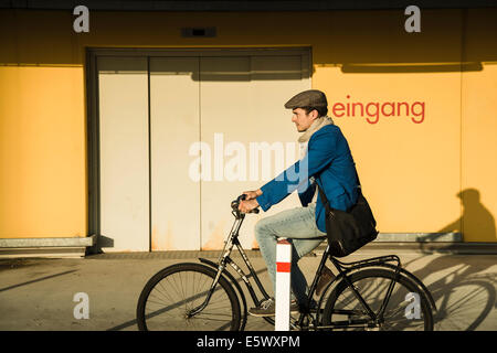 Giovane uomo escursioni in bicicletta lungo la strada urbana Foto Stock
