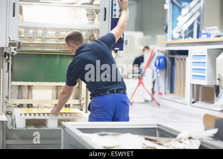 Lavoratore utilizzando la macchina in imballaggi di carta la fabbrica Foto Stock