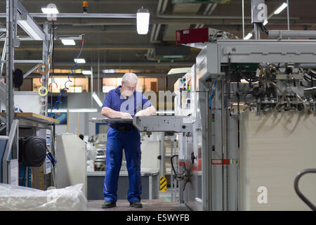 Lavoratore utilizzando la macchina in imballaggi di carta la fabbrica Foto Stock