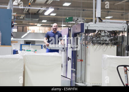 Lavoratore utilizzando la macchina in imballaggi di carta la fabbrica Foto Stock