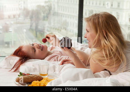 Prima colazione a letto: Donne sdraiate a letto con una tazza di caffè,  vassoio con croissant e vasetto di marmellata Foto stock - Alamy