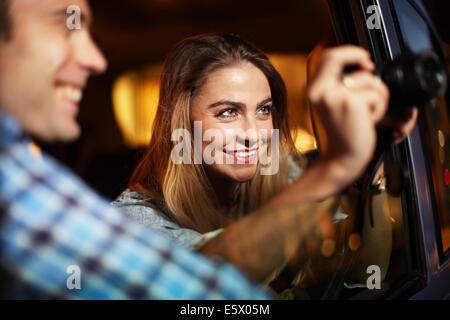 Giovane fotografa al di fuori della città taxi finestra la notte Foto Stock