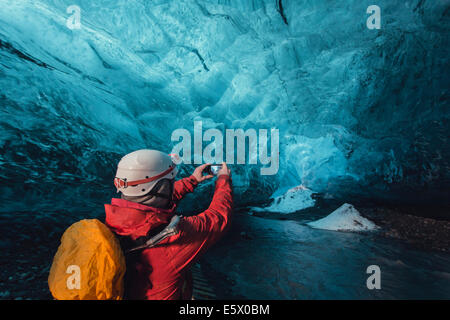 Uomo di fotografare la grotta di ghiaccio con lo smartphone, ghiacciaio Vatnajokull, Vatnajokull National Park, Islanda Foto Stock