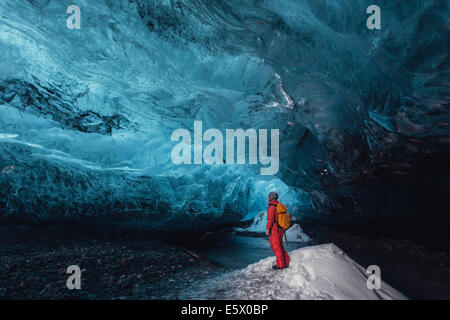 Uomo che guarda verso l'alto nella caverna di ghiaccio, ghiacciaio Vatnajokull, Vatnajokull National Park, Islanda Foto Stock