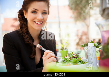 Giovane donna adulta mangiare insalata, esterno Foto Stock