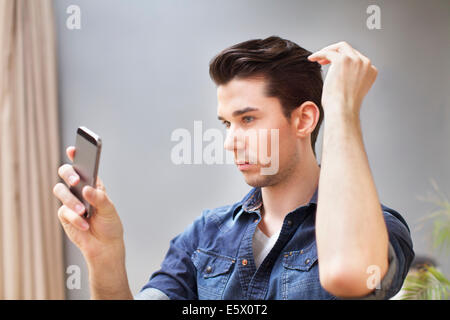 Giovane uomo prendendo selfie sullo smartphone in salotto Foto Stock