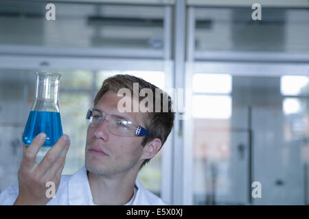 Giovane maschio scienziato mantenendo la beuta di Erlenmeyer in laboratorio Foto Stock