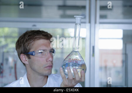 Giovane maschio scienziato azienda fino in matraccio tarato in laboratorio Foto Stock