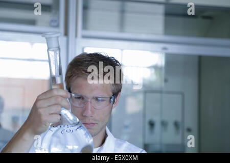 Giovane maschio scienziato analizzando pallone tarato in laboratorio Foto Stock