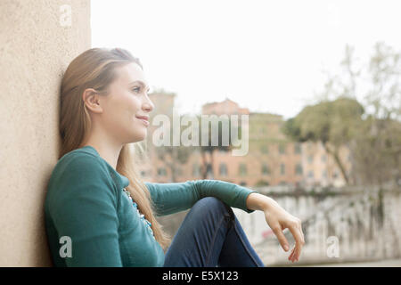 Giovane donna appoggiata contro la parete, l'Isola Tiberina, Roma, Italia Foto Stock