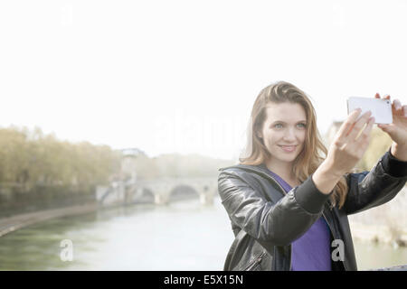 Giovane donna di scattare una foto di sé, l'Isola Tiberina, Roma, Italia Foto Stock