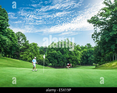 Due giovani golfisti maschio competere sul golf green, Apex, North Carolina, STATI UNITI D'AMERICA Foto Stock