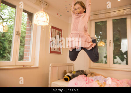 Ragazza divertirsi saltando metà aria dal letto in camera da letto Foto Stock