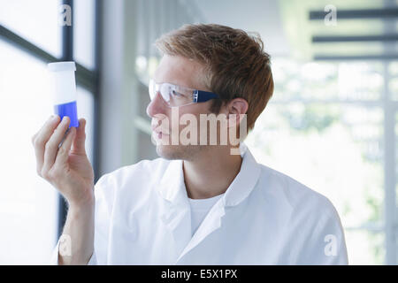 Scienziato maschio analizzando il campione in bottiglia di plastica in laboratorio Foto Stock