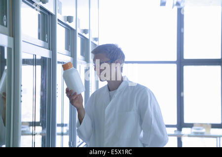 Giovane maschio scienziato guardando la bottiglia di plastica in laboratorio Foto Stock