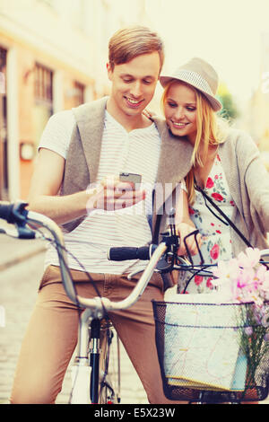 Giovane con lo smartphone e biciclette in città Foto Stock