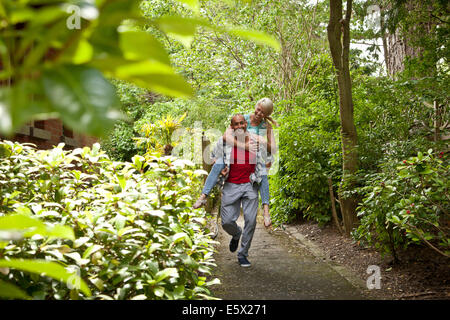 Coppia felice avendo divertimento dando piggy back in giardino Foto Stock