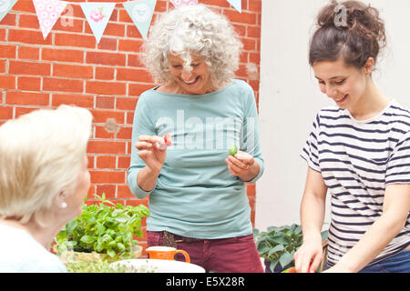 Tre donne preparano piatti freschi a Tavolo da giardino Foto Stock