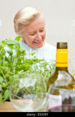 Senior donna seduta al tavolo da giardino Foto Stock