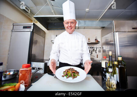 Immagine di chef di sesso maschile che serve insalate su piastra Foto Stock