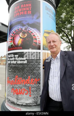 Berlino, Germania. 07 Ago, 2014. Klaus Staeck sorge accanto a una colonna di pubblicità con il suo poster al di fuori della Nuova Galleria Nazionale di Berlino, Germania, 07 agosto 2014. Il suo progetto 'Die Kunst findet nicht im Saale statt' (arte non accadere in Saale) è stato presentato nel corso di una conferenza stampa con dieci dei suoi manifesti politici degli anni settanta su 300 colonne di pubblicità in tutta la città per tre settimane. Foto: WOLFGANG KUMM/dpa/Alamy Live News Foto Stock