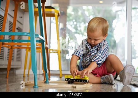 Bimbi maschio giocando con il treno impostato sul pavimento della cucina Foto Stock