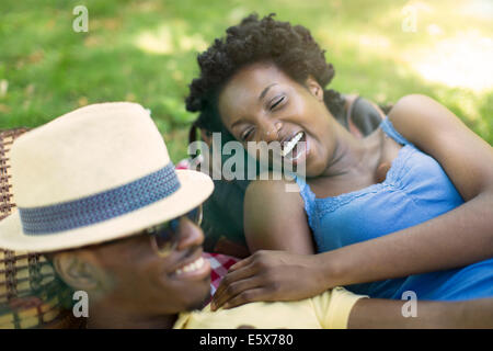 Giovane coppia giacendo in park ridere insieme Foto Stock