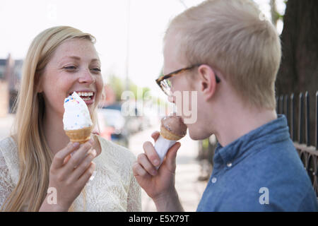 Coppia giovane mangiare coni gelato su strada Foto Stock