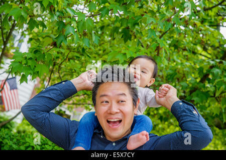 La metà degli adulti spalla padre bambino portando il figlio in giardino Foto Stock