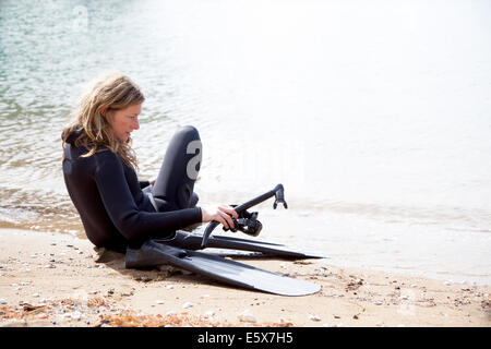 Metà femmina adulta scuba diver preparando a calarsi sulla spiaggia Foto Stock