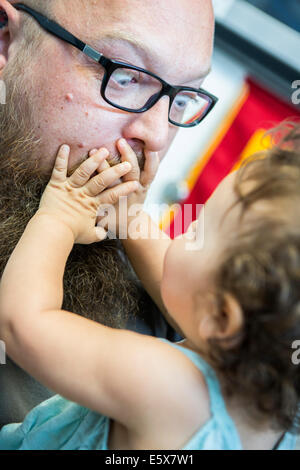 Close up della bambina con le mani sopra la bocca dell'uomo, Foto Stock