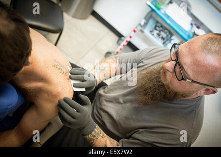 Tattoo Artist finendo un tatuaggio fresco Foto Stock