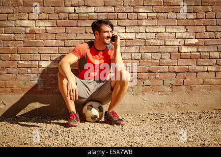 Maschio giovane giocatore di calcio in chat sullo smartphone Foto Stock