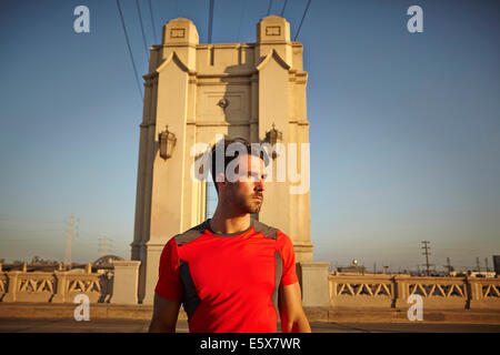 Giovane maschio runner prendendo una pausa al ponte della città Foto Stock