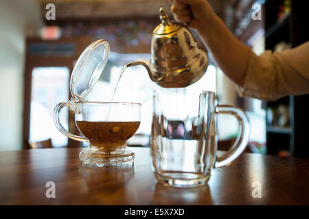 Mano femmina versando il tè sul contatore cafe Foto Stock